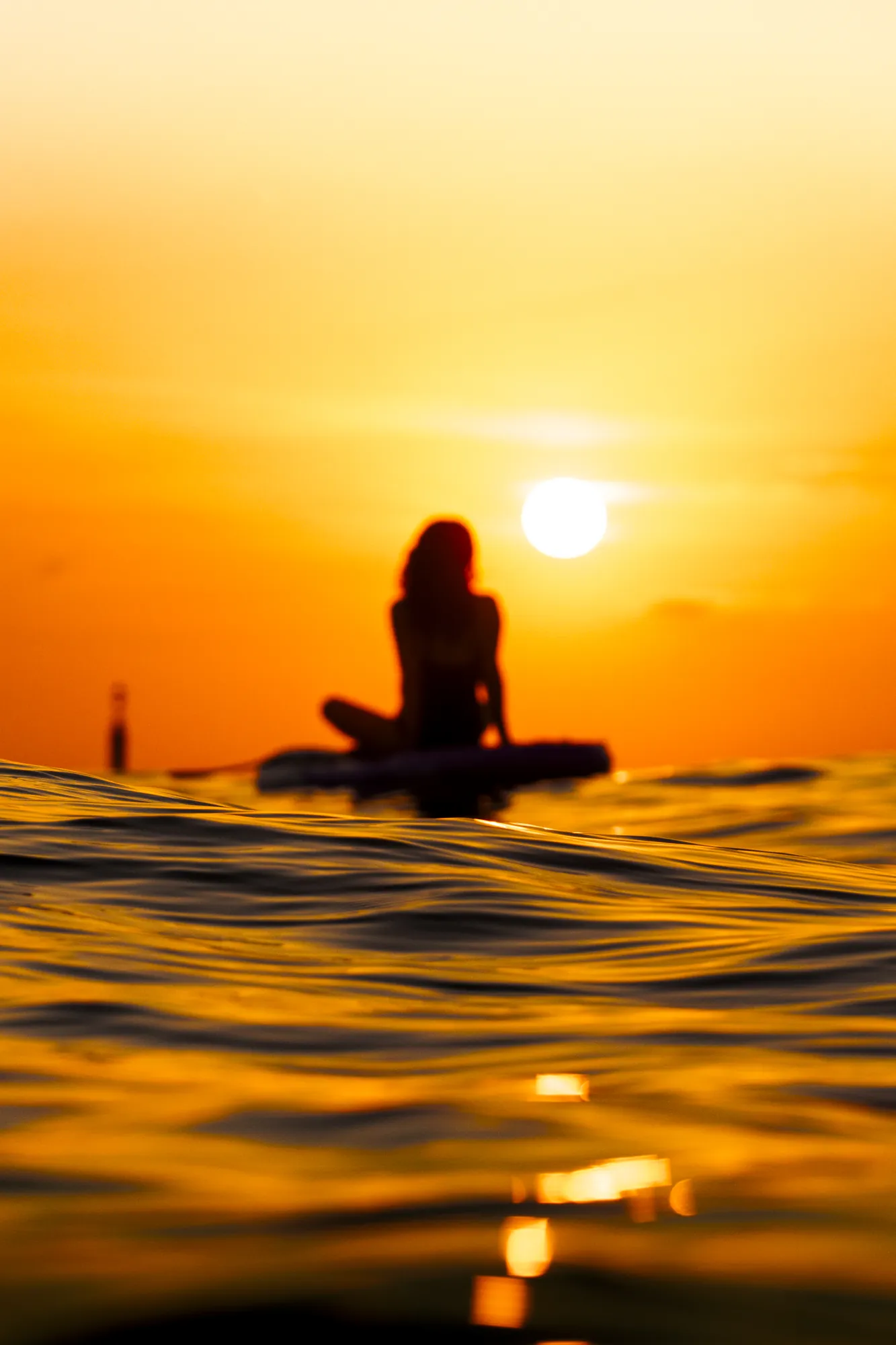Woman on a paddle board at sunrise in Sitges, calm sea at Riera Xica